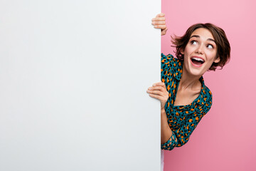 Poster - Portrait of overjoyed woman with bob hair wear print blouse hold white wall look at offer empty space isolated on pink color background