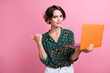 © deagreez - Portrait of positive cheerful woman wear print blouse hold laptop indicating at discount empty space isolated on pink color background