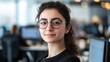 © Molly P - This portrait features a young Middle Eastern woman with glasses in a modern office setting. Her confident expression and stylish look capture a blend of professionalism and warmth.