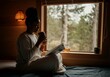 © Anna - Young black woman sitting in a cozy eco-lodge room, sipping herbal tea from a reusable cup while reading an eco-tourism guide. Concept of commitment to sustainable travel, eco-tourism
