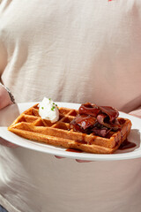 Wall Mural - Man holding plate of fresh waffle with beef brisket and cream cheese