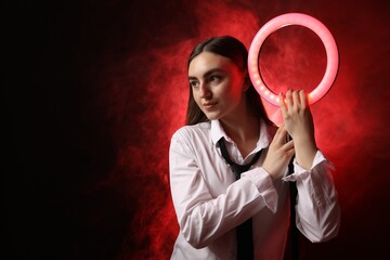 Canvas Print - Beautiful woman with ring lamp on dark red background in smoke, space for text