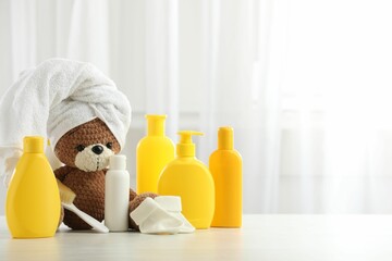 Wall Mural - Baby cosmetic products, socks, brush and toy bear with towel on light wooden table indoors. Space for text