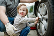 © MNStudio - Cute little boy helping his father to change car wheels at their backyard. Father teaching his little son to use tools.