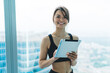 © BullRun - Half length portrait of beautiful slim woman in activewear holding modern digital tablet for blogging, cheerful hipster girl sending mails and communicating via tablet connected to 4G internet