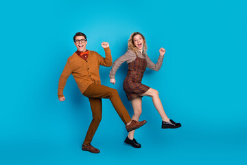 Wall Mural - Young couple joyfully dancing in vintage-inspired outfits against solid blue background