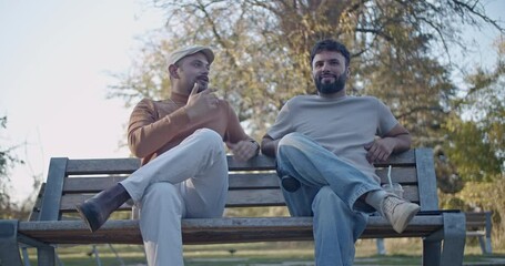 Poster - Two friends sit on a park bench, engrossed in conversation. Their facial expressions shift from thoughtful contemplation to amusement as they share a moment of connection.