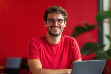 Poster - Developer Smiling While Working on Laptop in a Vibrant Red Office Space. Generative AI