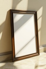 Poster - Empty picture frame resting against a beige wall in a sunlit room creating a serene atmosphere