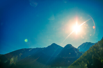 Wall Mural - silhouette of mountains against a clear blue sky with sun