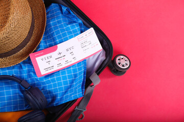 Sticker - Travel abroad. Packed suitcase with ticket on red background, above view