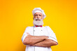 © deagreez - Portrait of a confident senior chef wearing a traditional uniform standing with crossed arms against vibrant yellow background