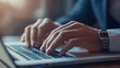© mahamad - Close-up of a businessman's hands typing on a laptop keyboard.