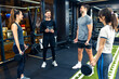 © Mediteraneo - Group of people have group training with barbell weights while their personal trainer is explaining and counting sets.