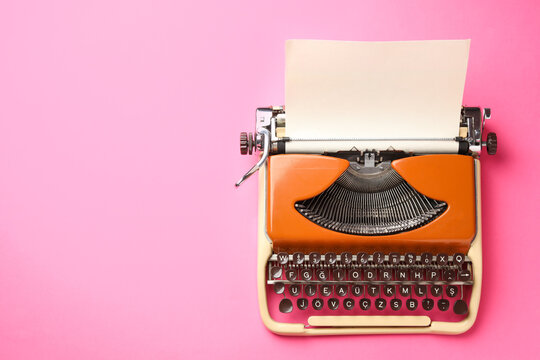 Vintage typewriter with sheet of paper on pink background, top view. Space for text