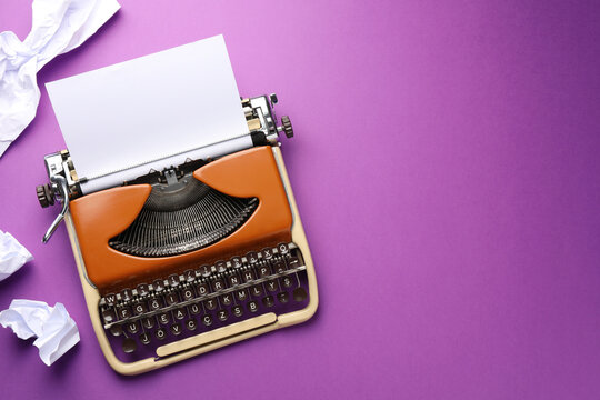 Vintage typewriter with sheet and crumpled paper on purple background, top view. Space for text