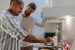 © bernardbodo - Happy gay couple preparing breakfast together in a modern kitchen, enjoying their time