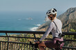 © KatyaPulka - Female cyclist pauses on scenic coastal road, enjoying breathtaking ocean views.  Perfect for travel, sports, and active lifestyle themes.