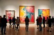 © Vadym - People stand, look at colorful abstract paintings in art gallery. Many visitors explore modern exhibition. Gallery setting houses abstract art. Visitors from various backgrounds enjoy colourful