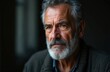 © Vadym - Closeup portrait of serious senior man with gray beard and mustache. He has thoughtful expression and is wearing casual attire. Image is focused on face and upper body, against dark background.