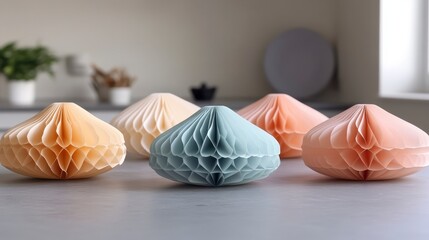 Poster - Group of pastel colored paper honeycomb decorative objects on a light gray countertop, showcasing various shades of peach, beige, and gray tones