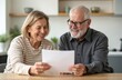 © Vadym - Happy senior couple reads good financial news. Look at important document with happy expressions. Document could bill payment, tax return, financial gain. Domestic scene in home setting.
