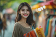© Chalita - A woman holding multiple shopping bags in her hands standing in a retail environment with a cheerful expression and casual attire