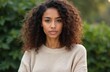 © Vadym - Young Hispanic woman with curly hair, casual attire looks directly at camera. Outdoor portrait shows confident expression. Natural beauty, fashion style. Lifestyle photo of attractive lady in 20s.