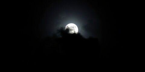 a full moon partially obscured by clouds in a dark night sky