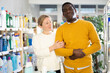 © JackF - In store, woman with African American man in household shop, looking for missing items in store window. Spouses, useful time together while shopping
