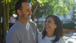 © Krakenimages.com - Middle age hispanic couple enjoying a loving moment together outdoors in a city park under sunlight reflecting happiness and warmth surrounded by green trees and urban setting.