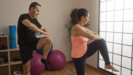 Sticker - Middle-aged hispanic couple practicing exercise indoors, featuring a man and woman in a gym setting, displaying love for fitness and healthy living together.