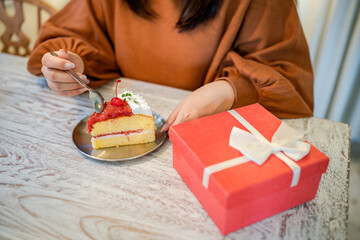 Happy Asian woman eating tasty Christmas fruit cake. Christmas Dinner Party with delicious piece of xmas cake New Year and Christmas concept