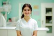 © BonzEarthsnapper - Smiling Healthcare Professional in White Uniform Standing in Modern Medical Office with Light Blue Walls and Equipment in Background