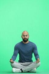 A man, on a green background, in full height, meditating