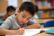 © Thanapipat - concept back to school A boy writing in a notebook at a classroom desk.