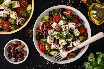 Wall Mural - Greek style salad - fresh vegetables with feta cheese, kalamata olives on black table