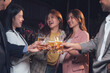 © Kritdanai - Cheers to Connection: A group of young professionals raise their glasses in a toast, their laughter and smiles illuminating the warm atmosphere of a social gathering.