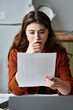 © LIGHTFIELD STUDIOS - Woman grappling with complex emotions while reading important documents at home