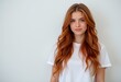 © Tatyana - Woman with long wavy ginger hair wearing a white t-shirt posing against a plain background with soft lighting