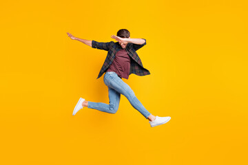 Poster - Full body photo of cheerful content dream funky man jump have fun dance like true clubber enjoy summer vacation wear denim jeans sneakers checked green shirt isolated over yellow color background