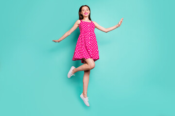 Wall Mural - Full size photo of lovely girl smiling jumping wearing polka dot skirt dress isolated over teal turquoise background