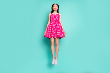 Wall Mural - full size photo of cute lady jumping with toothy smile wearing dotted skirt dress isolated over teal