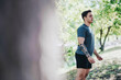 © qunica.com - A young man with a tattoo enjoys a morning workout in a sunlit park. He wears casual athletic attire while surrounded by lush greenery, embodying fitness and outdoor enjoyment.