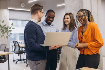smiling diverse professionals collaborating, sharing laughter during team project at modern office, 
