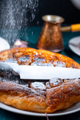 Wall Mural - Put a knife on the pie and sprinkle powdered sugar on top to get the contour of the knife on the pie. On a dark background, powdered sugar falls on a banana tart