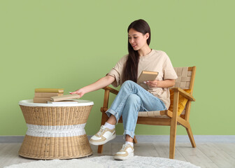 Wall Mural - Beautiful young woman taking book from coffee table at home