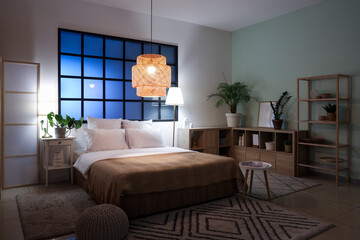 Poster - Interior of bedroom with comfortable bed, bedside table and glowing lamps