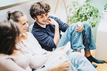 Poster - A cheerful group of young college students enjoying study time together indoors, surrounded by plants and cozy decor. They appear relaxed, happy, and engaged in conversation.