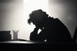 © Riya - silhouette of a person sitting at a desk looking stressed
